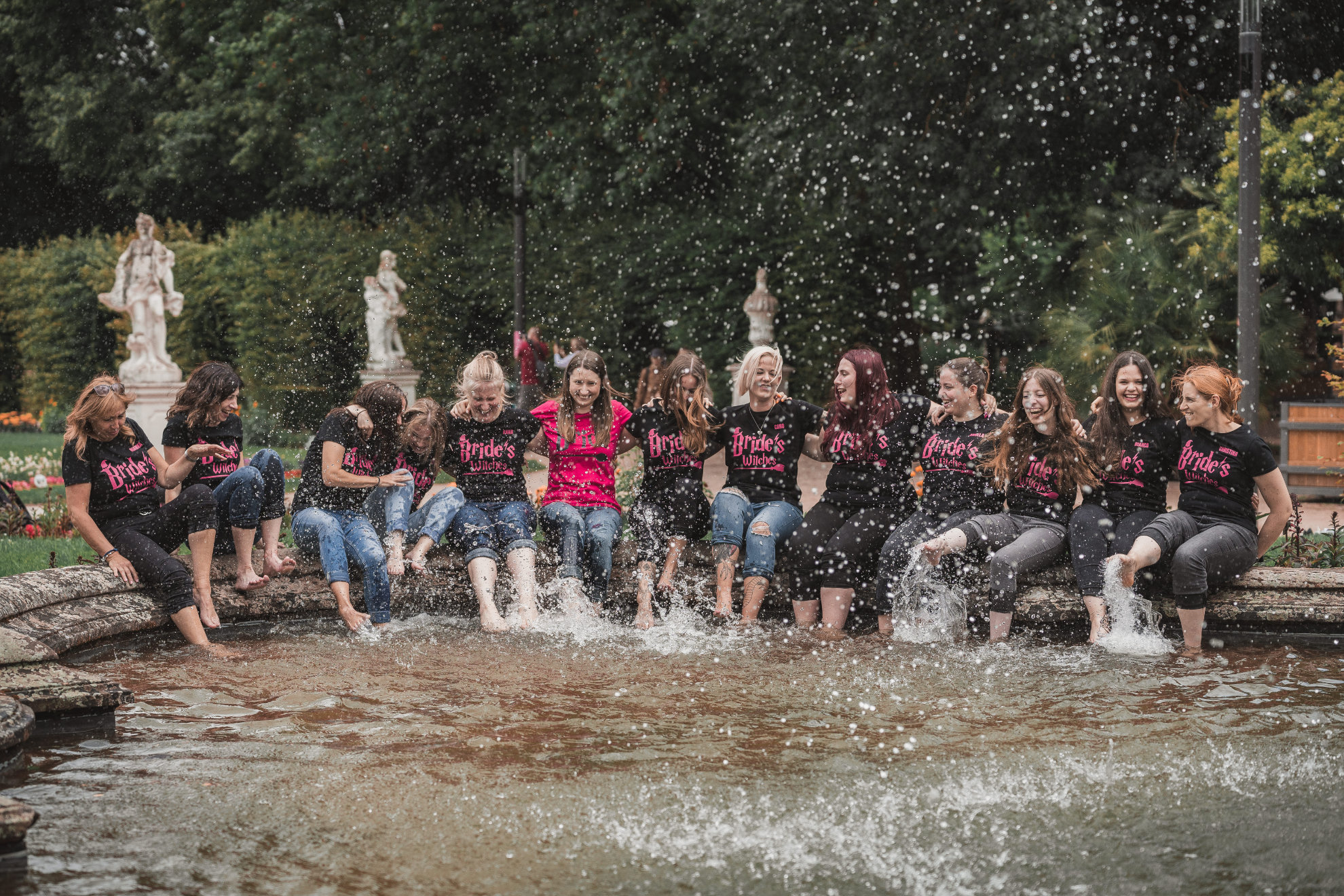 Gruppe sitzt am Brunnenrand und planscht mit den Füßen im Wasser