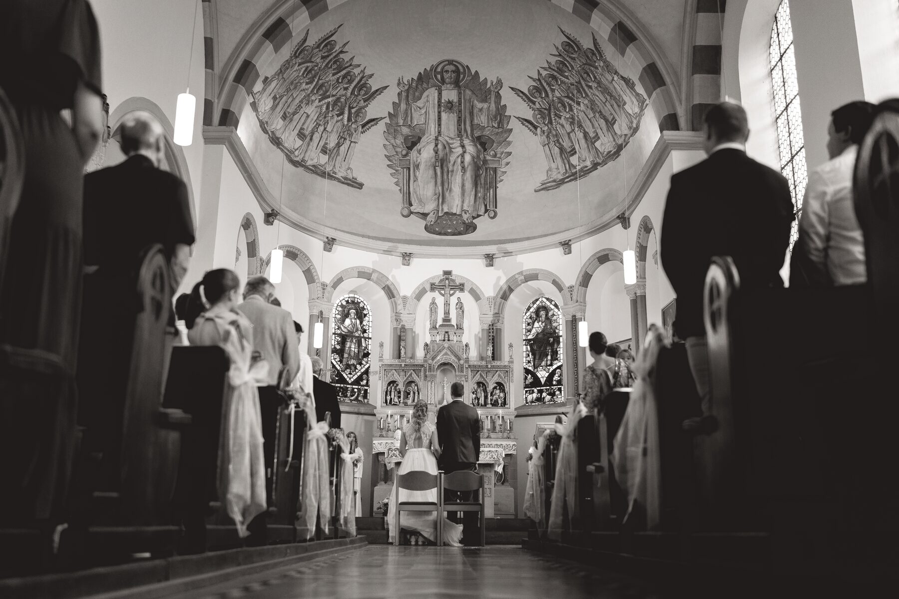 Blick durch die Kirche auf das Brautpaar am Altar, Schwarzweiß