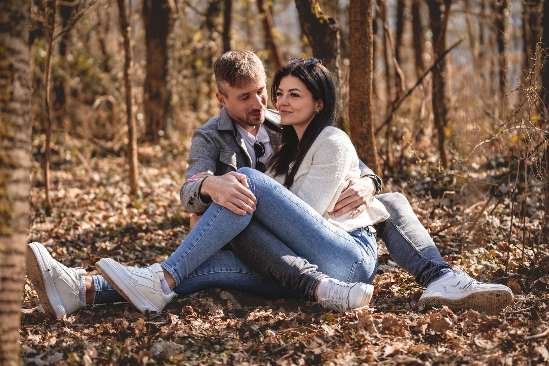 Paar sitzt zwischen Herbstlaub im Wald