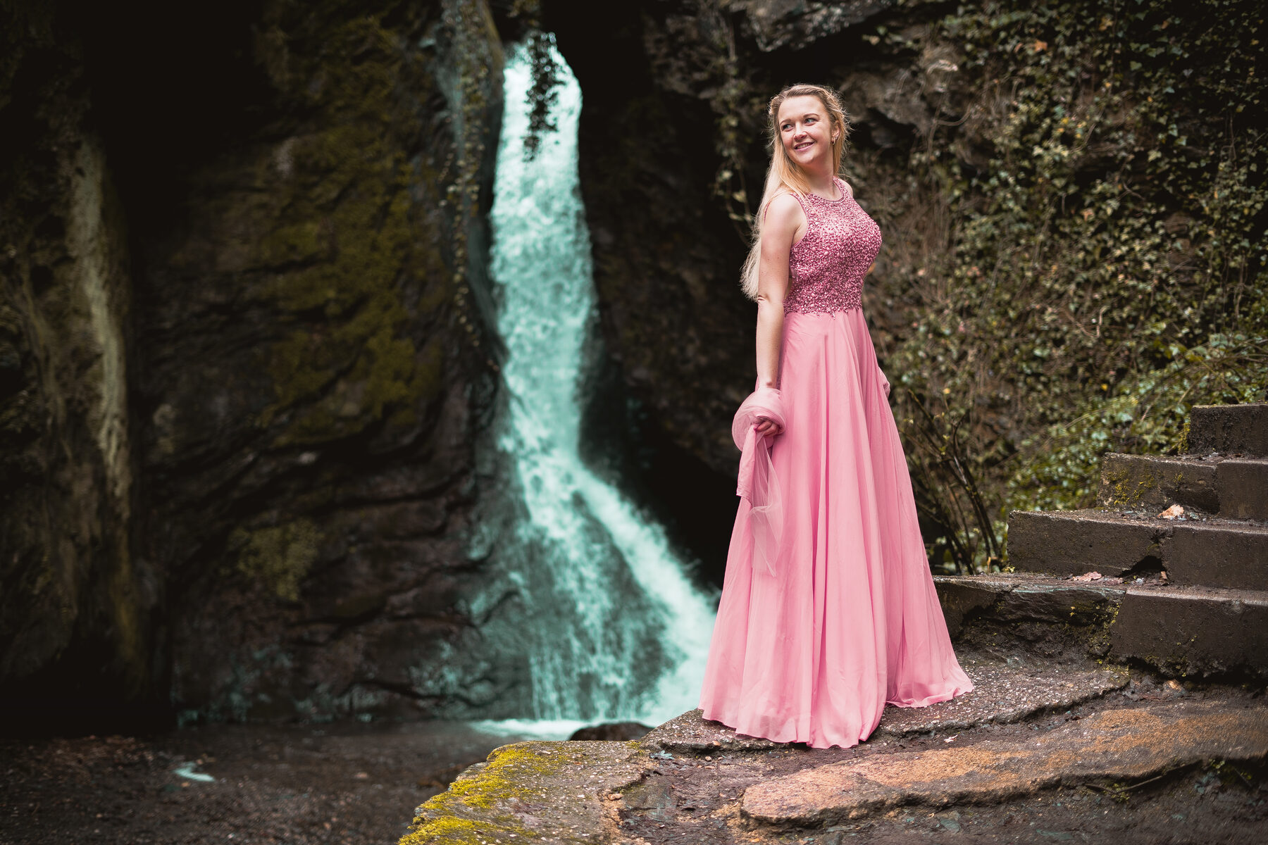 Frau im langen Kleid vor einem Wasserfall