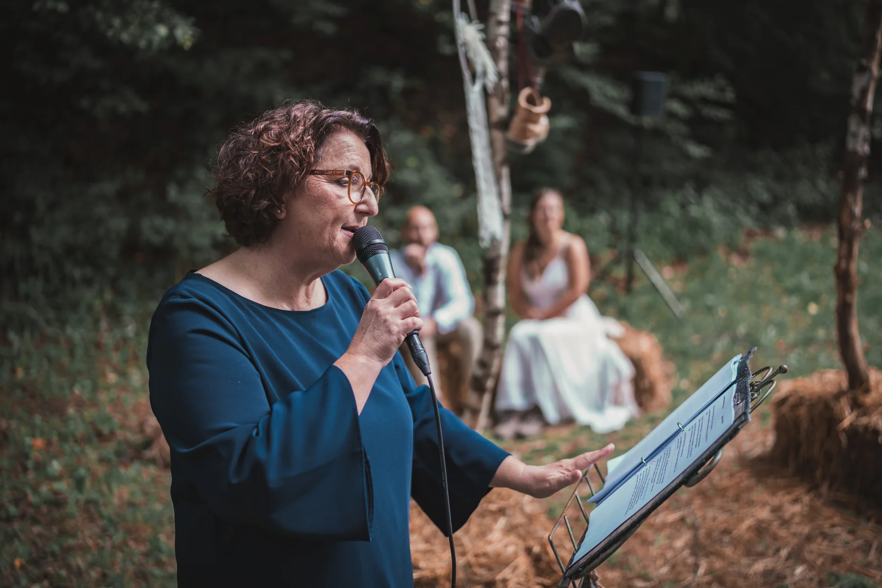 Petra Melzer hält die Traurede, im Hintergrund hören Braut und Bräutigam zu